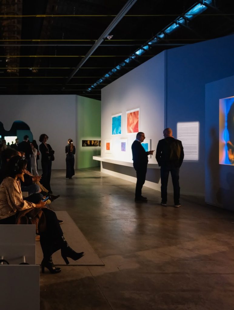 veduta dell'interno della mostra con persone che osservano le opere